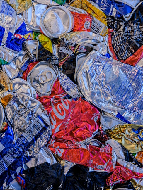 A collection of multiple overflowing rubbish bins and scattered waste items situated on a paved urban sidewalk in front of a commercial building. The scene includes a large metal recycling container l